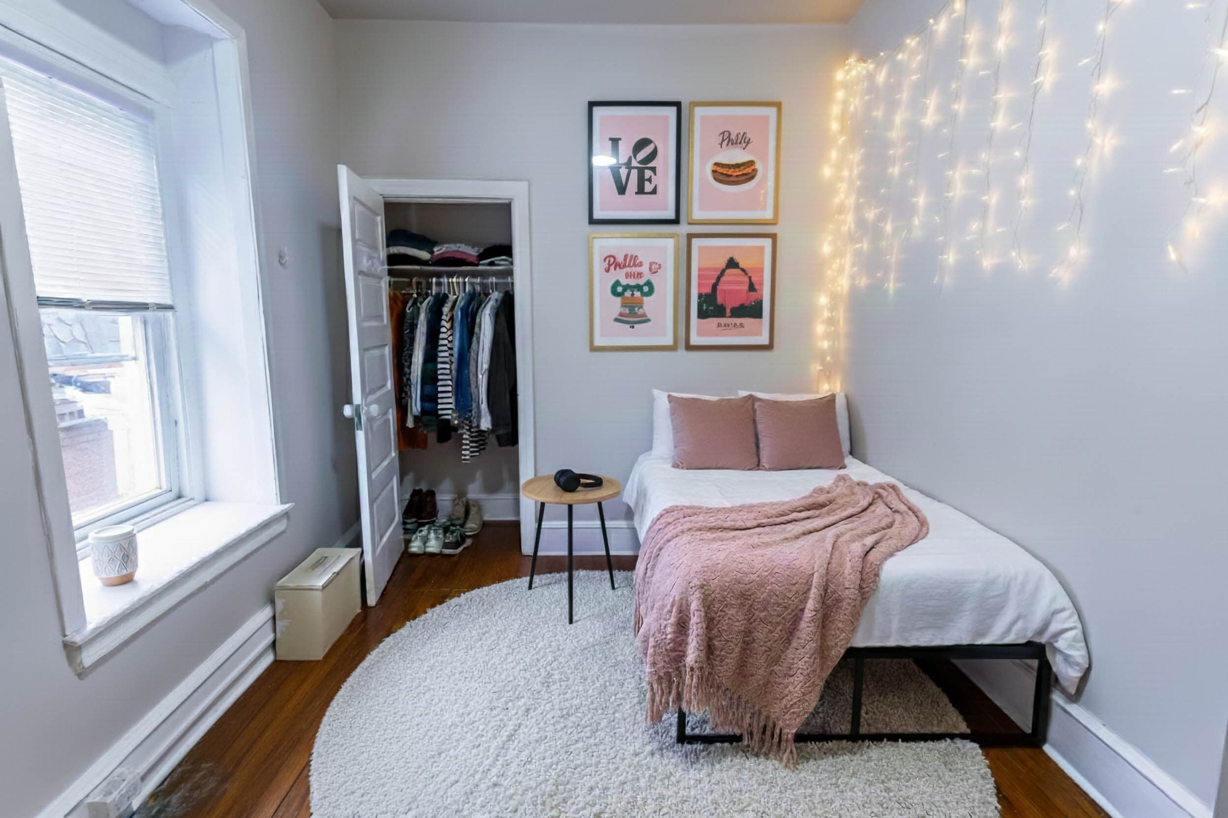 The open bedroom, staged with a bed, closet, and string lights